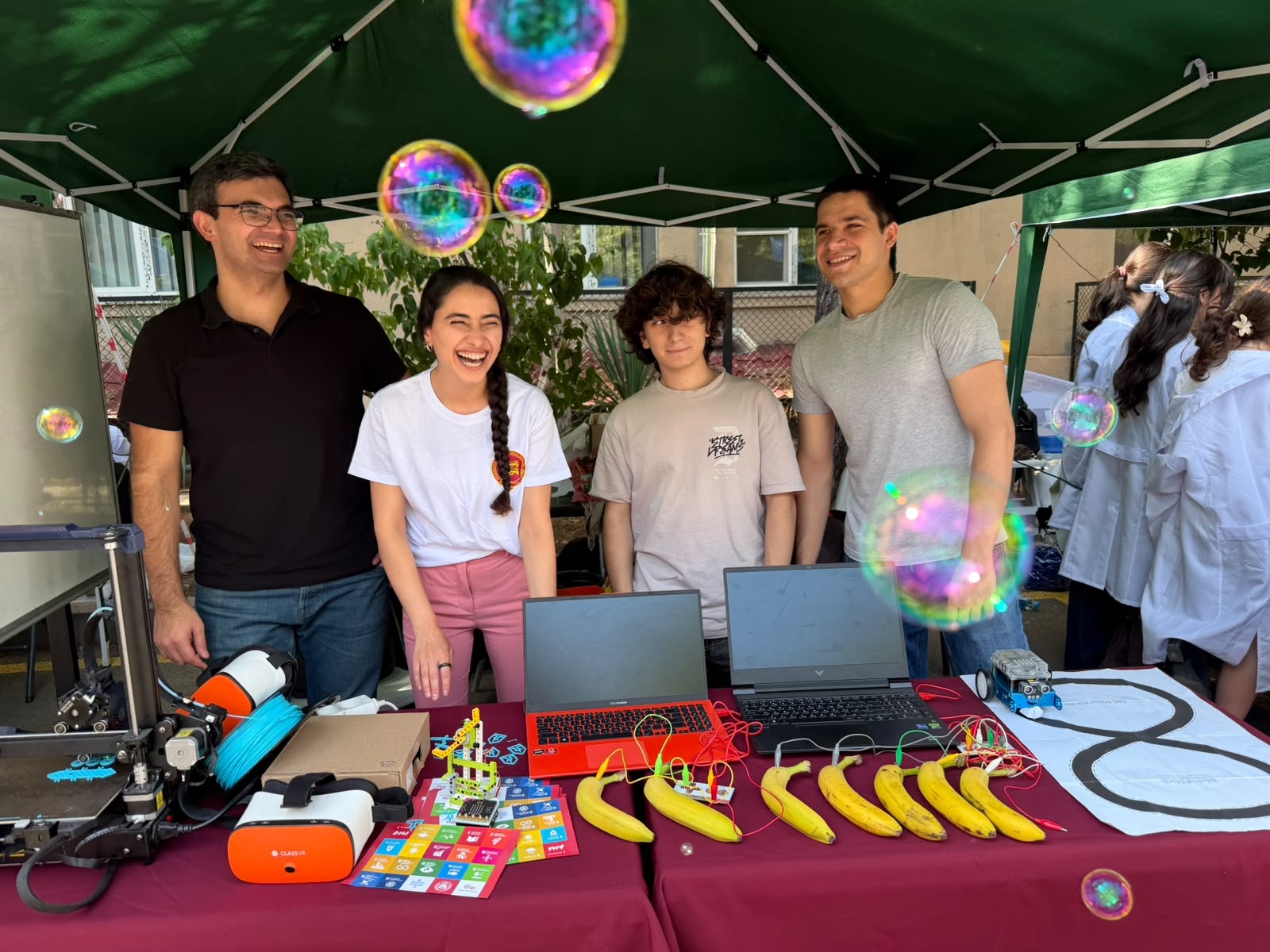 The Buckswood International School Tbilisi technology team at their stand, with VR headsets, a 3D printer, robots and laptops